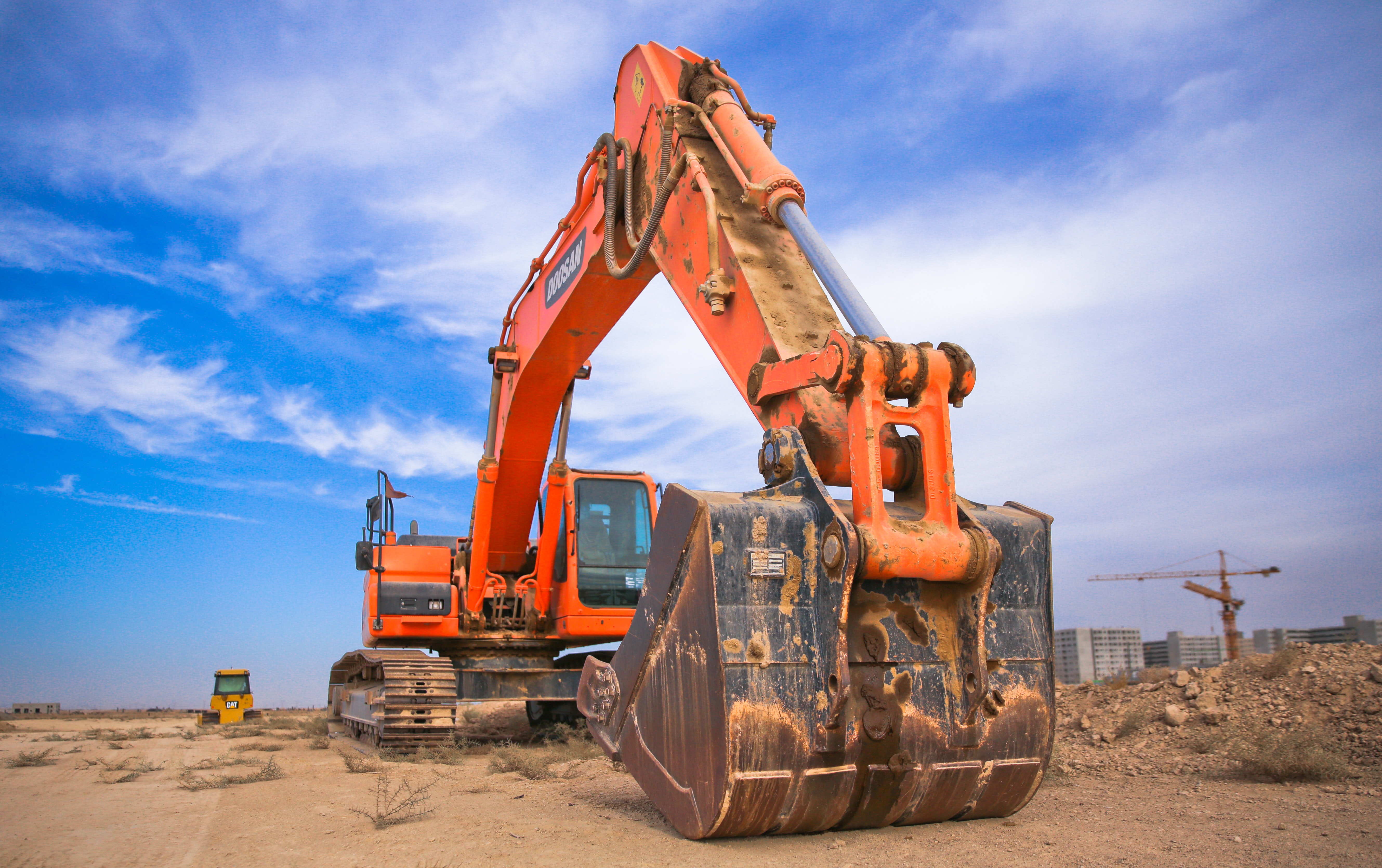 low angle photography of orange excavator under white clouds 1078884